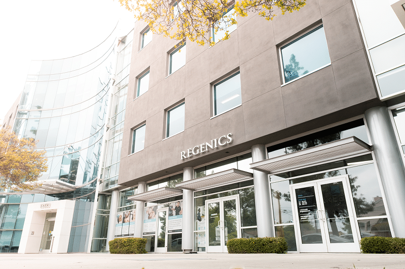 Nestled among lush trees, the modern office building features glass windows and proudly displays the "REGENICS" signage. Inside, every corner reflects our "About Us" ethos—a blend of innovation and commitment to excellence.